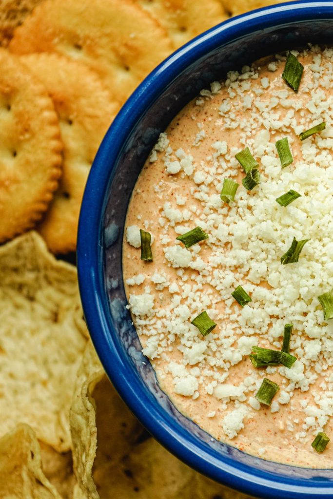 This is Mexican sour cream dip in a bowl with tortilla chips and crackers in the background.