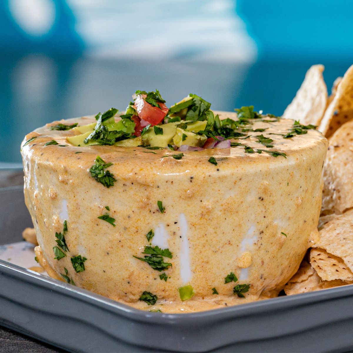 This is a queso in a bowl with tortilla chips in the background
