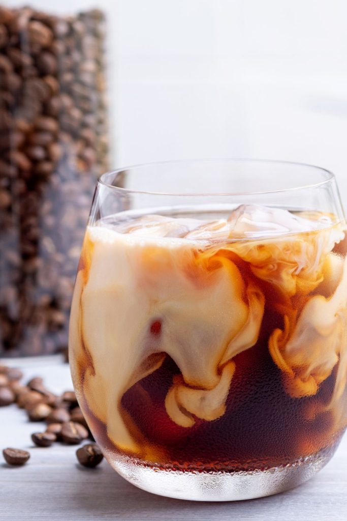 This is iced coffee with heavy cream and coffee beans in the background.
