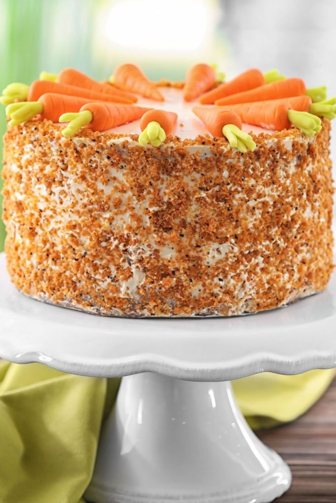 This is a whole carrot cake on a cake stand. 