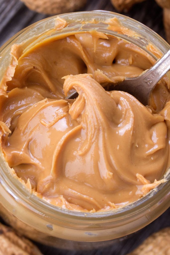 This is a closeup of an open jar of peanut butter with a spoon.